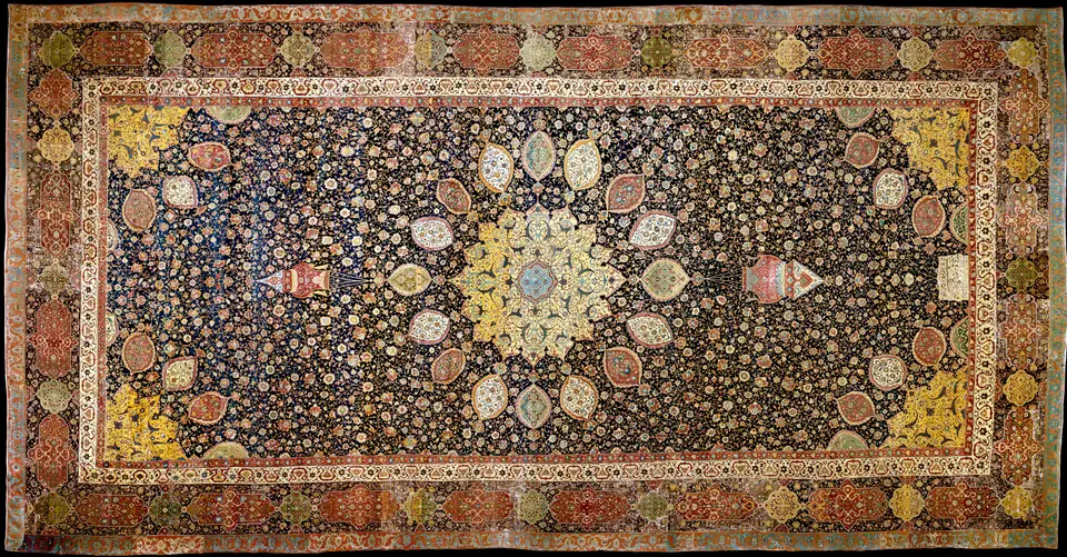 A very large carpet with a central medallion surrounded by smaller ovals and a dense pattern of flowers on a dark blue background.
