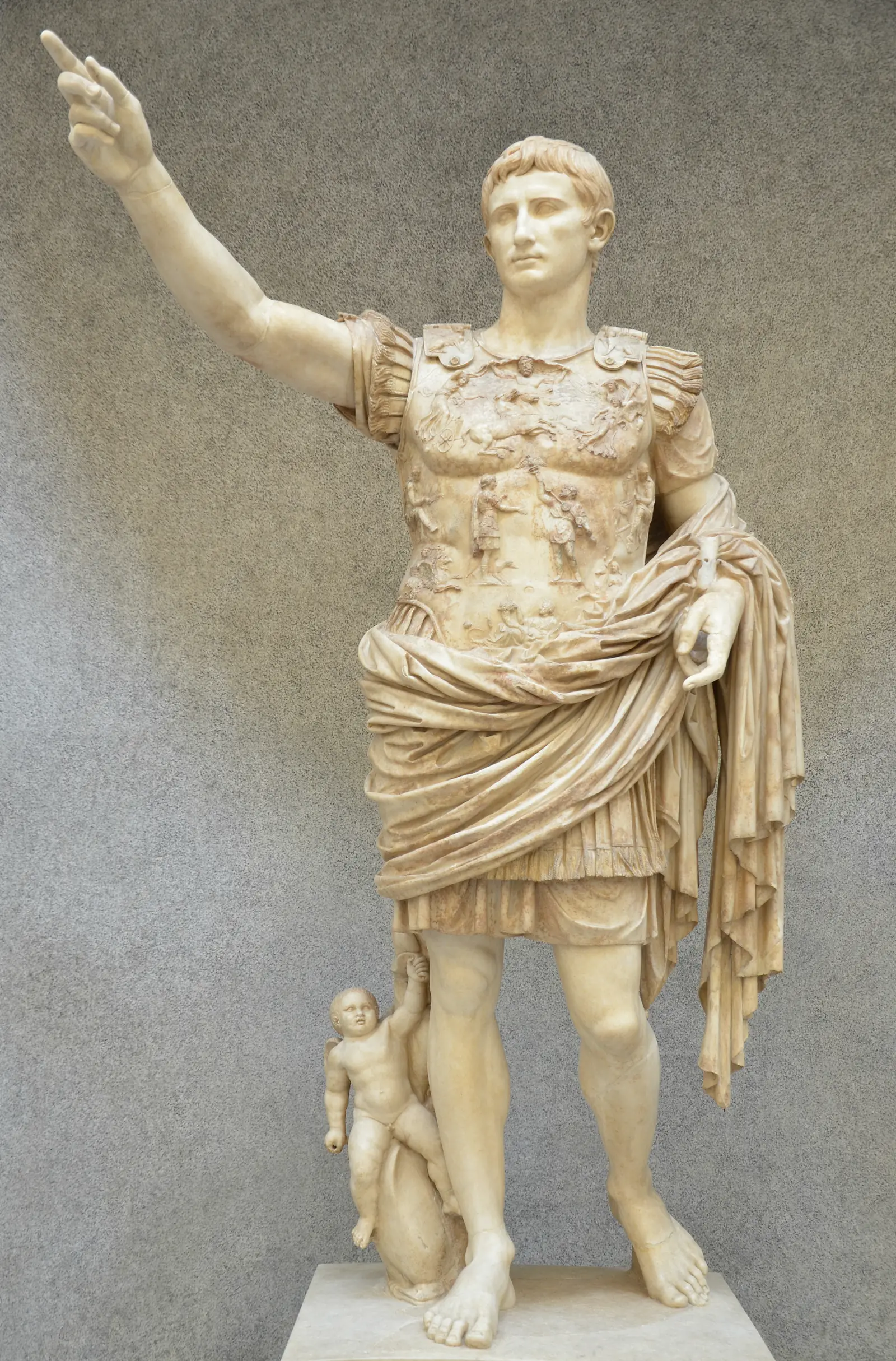 A marble statue of a man in a carved breastplate raising his right arm, with a small winged child riding a dolphin at his leg.