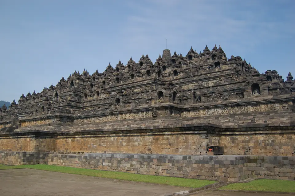 A huge stepped stone monument with terraces of carved walls rising to rows of small bell-shaped domes.