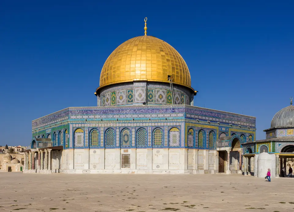 An octagonal building with a large golden dome and walls covered in blue tiles.