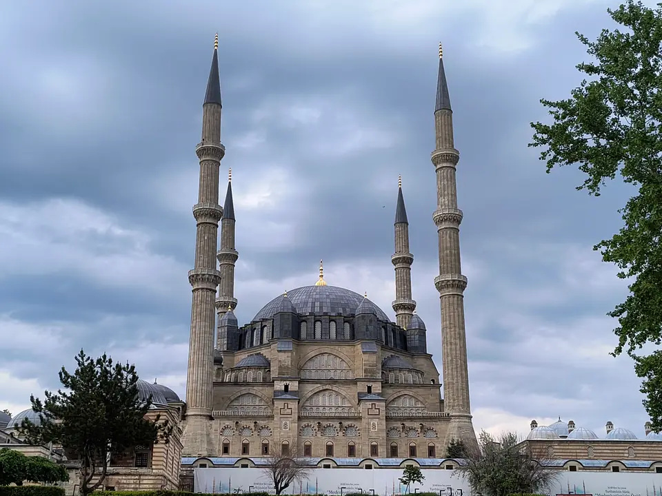 A large mosque with a broad central dome, smaller domes and half domes, and four very tall, slender towers at its corners.