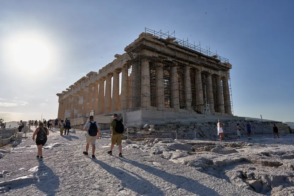 The west end of a ruined marble temple with a row of columns under a triangular gable.