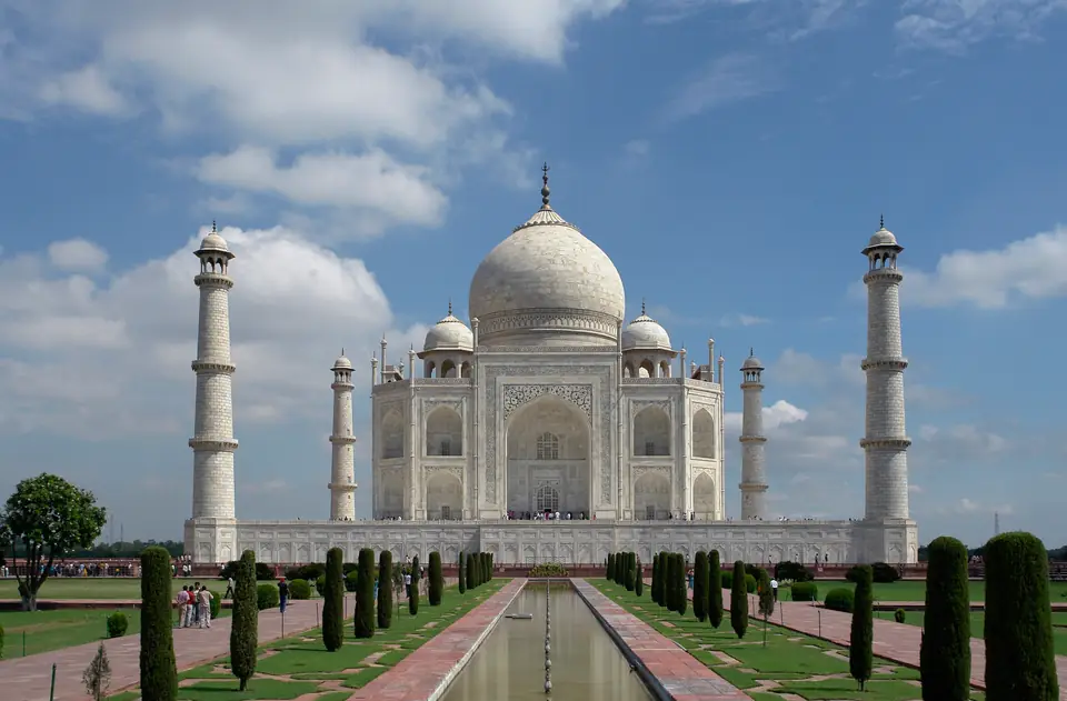 A white marble tomb with a large dome and four minarets reflected in a long pool.