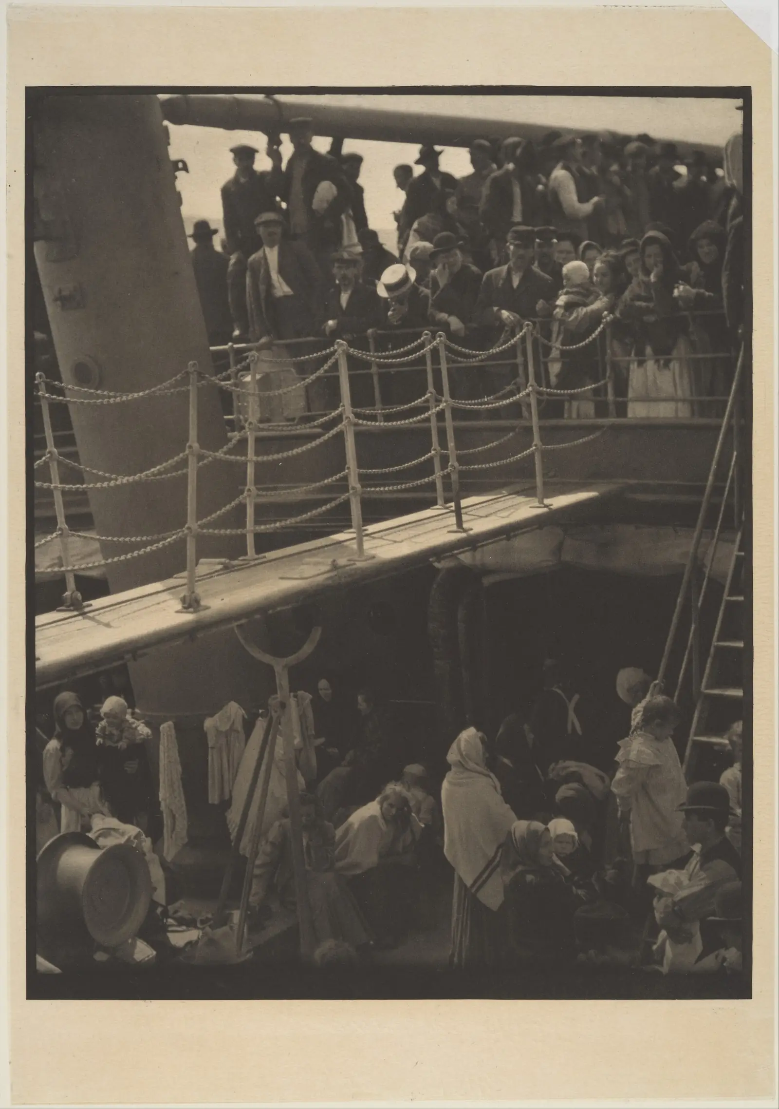 A photograph of a crowded ship with passengers on a lower deck and an upper deck, divided by a slanting gangway.