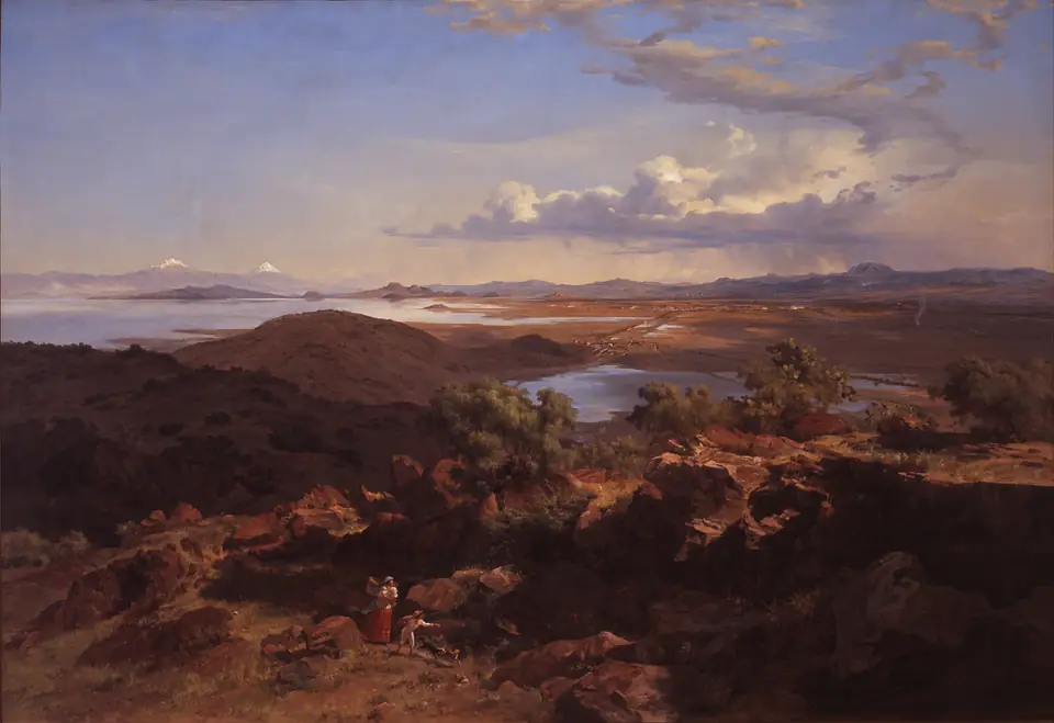 A wide, sunny panorama from a hillside over a valley with lakes, a distant city and snow-capped volcanoes.