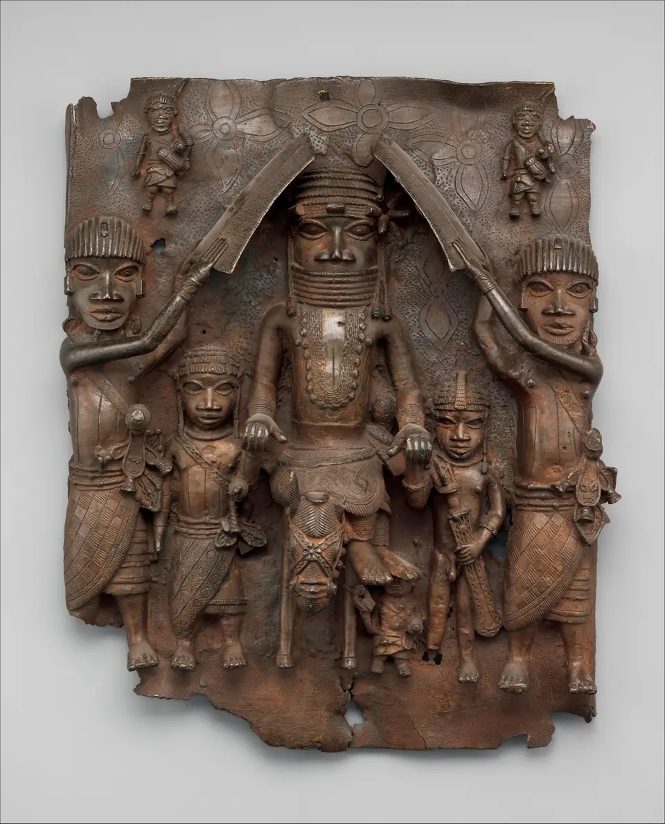 A brass plaque in high relief: a large central figure sits sideways on a small horse, flanked by two attendants who raise shields over his head, with smaller figures beside him and two tiny figures at the top corners.
